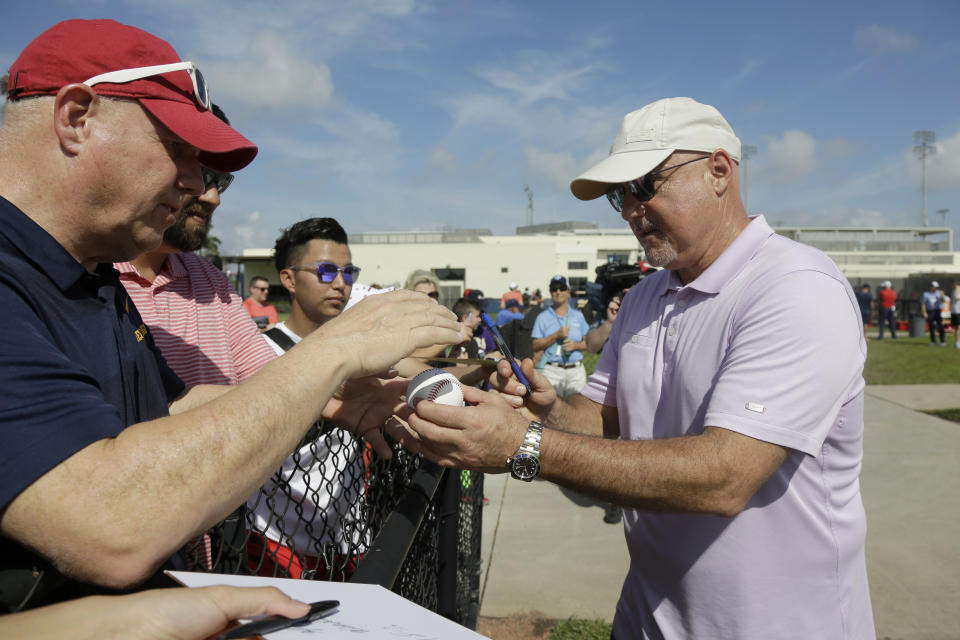 Washington Nationals general manager Mike Rizzo, right, signs autographs for fans during spring training baseball practice Friday, Feb. 14, 2020, in West Palm Beach, Fla. (AP Photo/Jeff Roberson)