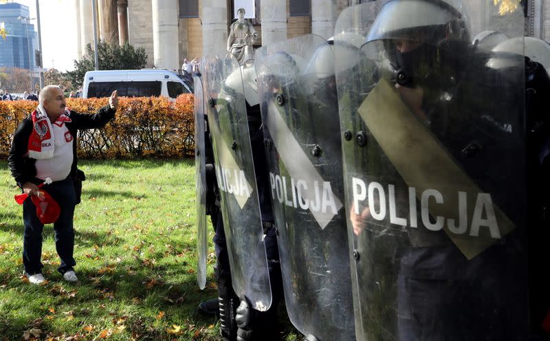 A demonstrator stands in front of the police during anti lockdown protest as the government announced additional restrictions to prevent spread of the coronavirus disease (COVID-19) in Warsaw