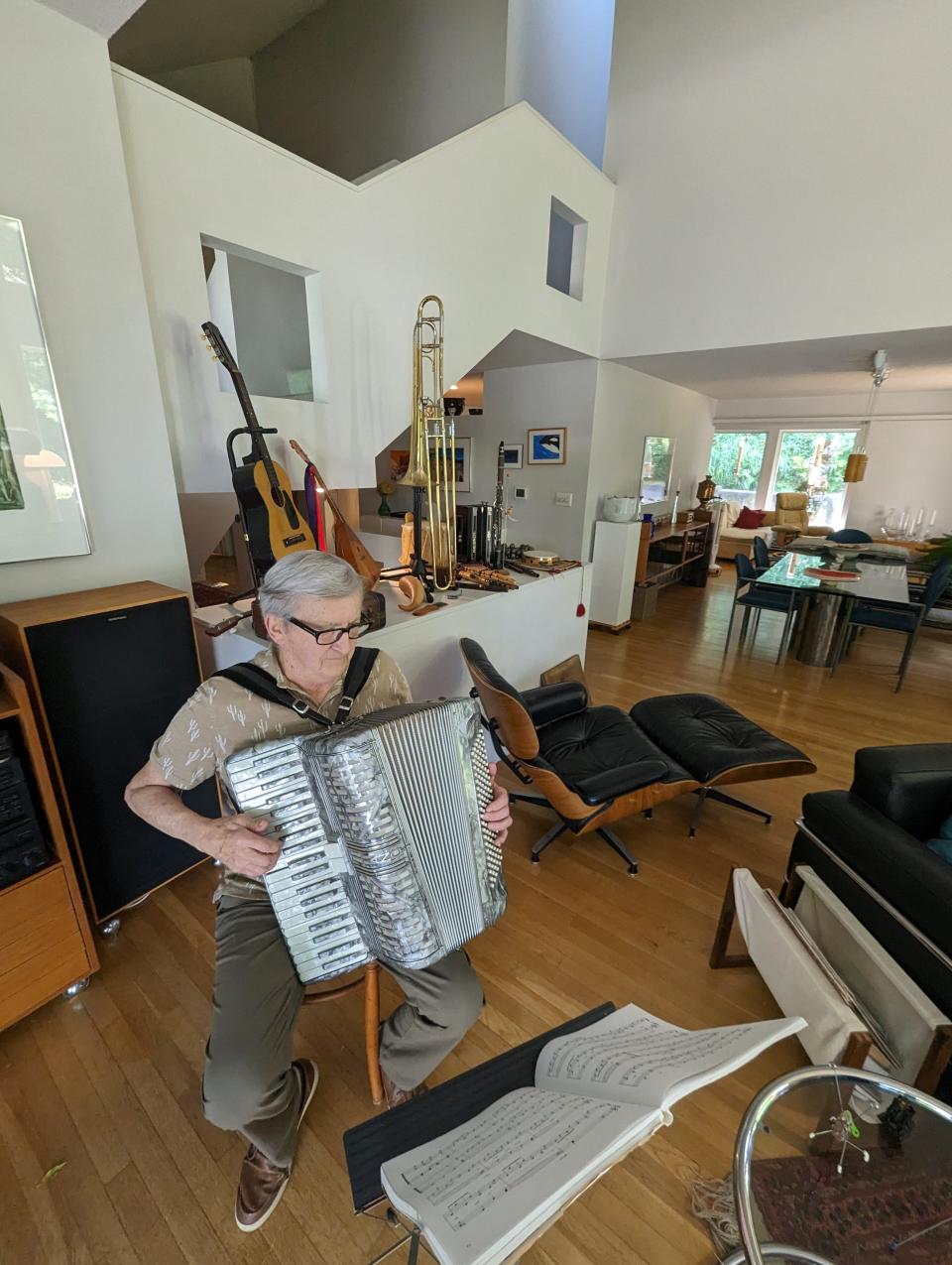 Bill Nowysz practices his accordion in the interesting home he designed in the 1970s. As seen in the background, he also enjoys collecting musical instruments.