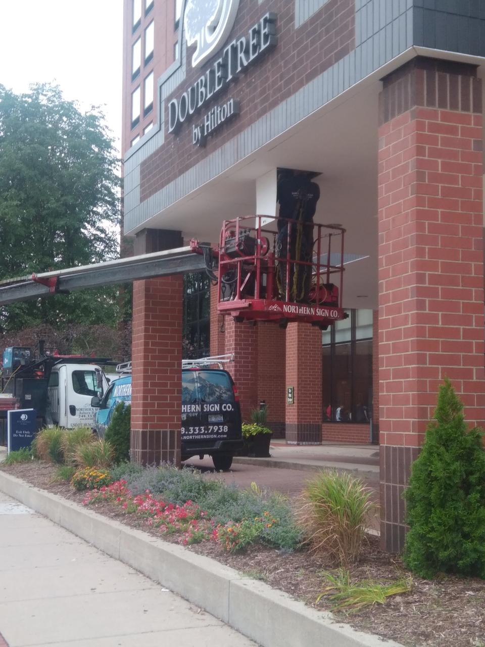 A crew works to install a new sign at the DoubleTree by Hilton hotel on North Grand Avenue in downtown Lansing on Friday, Sept. 8, 2023