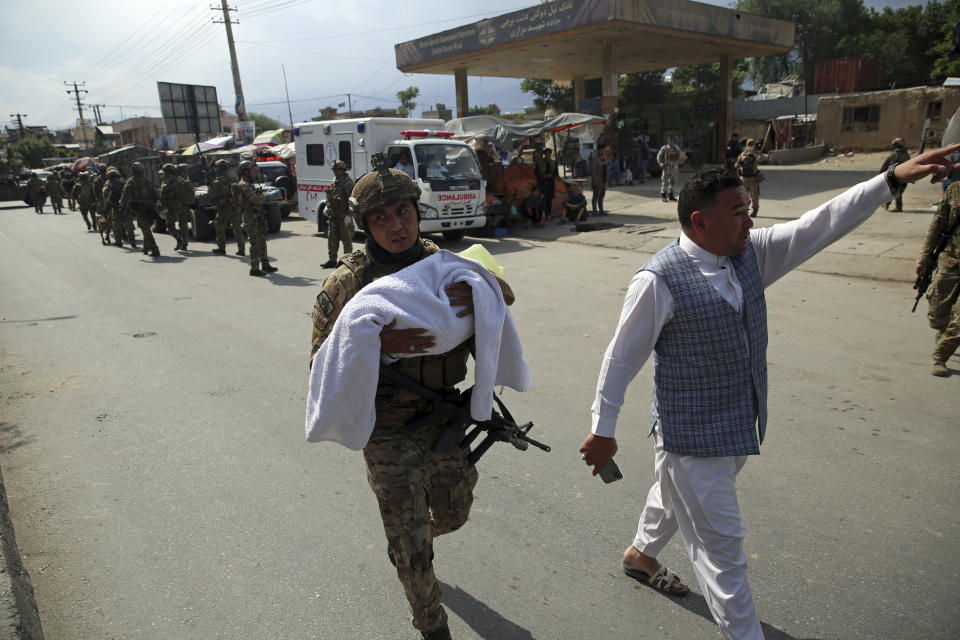 An Afghan security officer carries a baby after gunmen attacked a maternity hospital, in Kabul, Afghanistan, Tuesday, May 12, 2020. Gunmen stormed the hospital in the western part of Kabul on Tuesday, setting off a shootout with the police and killing several people. (AP Photo/Rahmat Gul)