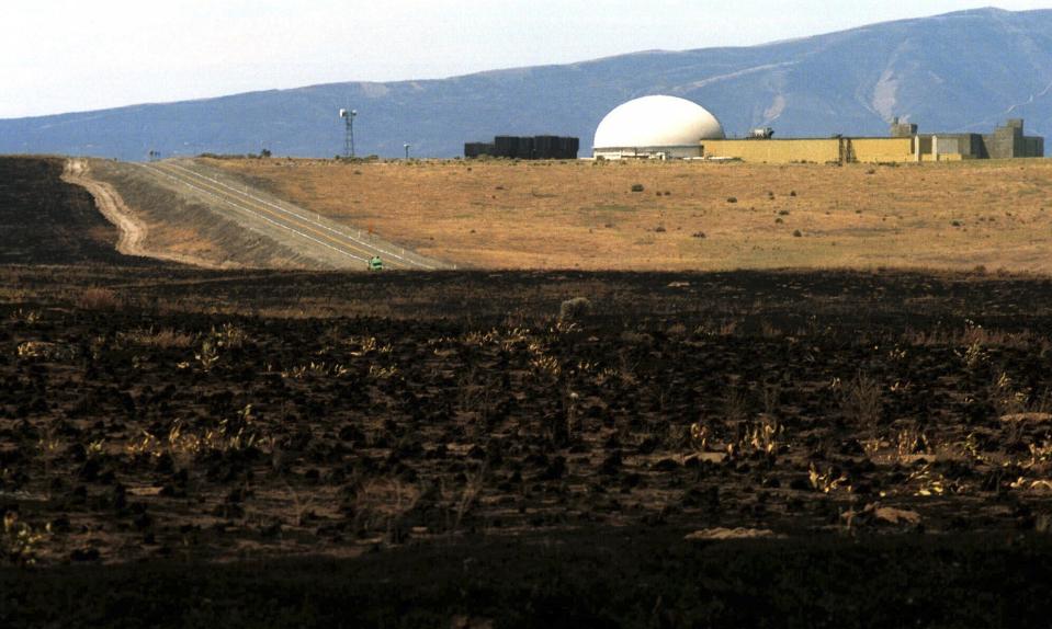 FILE - Burnt grass is seen after a wildfire near the Fast Flux Test Reactor on the Hanford nuclear reservation near Richland, Wash., June 30, 2000. Climate climate change increasingly threatens research laboratories, weapons sites and power plants across the nation that handle or are contaminated with radioactive material or perform critical energy and defense research. (AP Photo/Jackie Johnston, File)