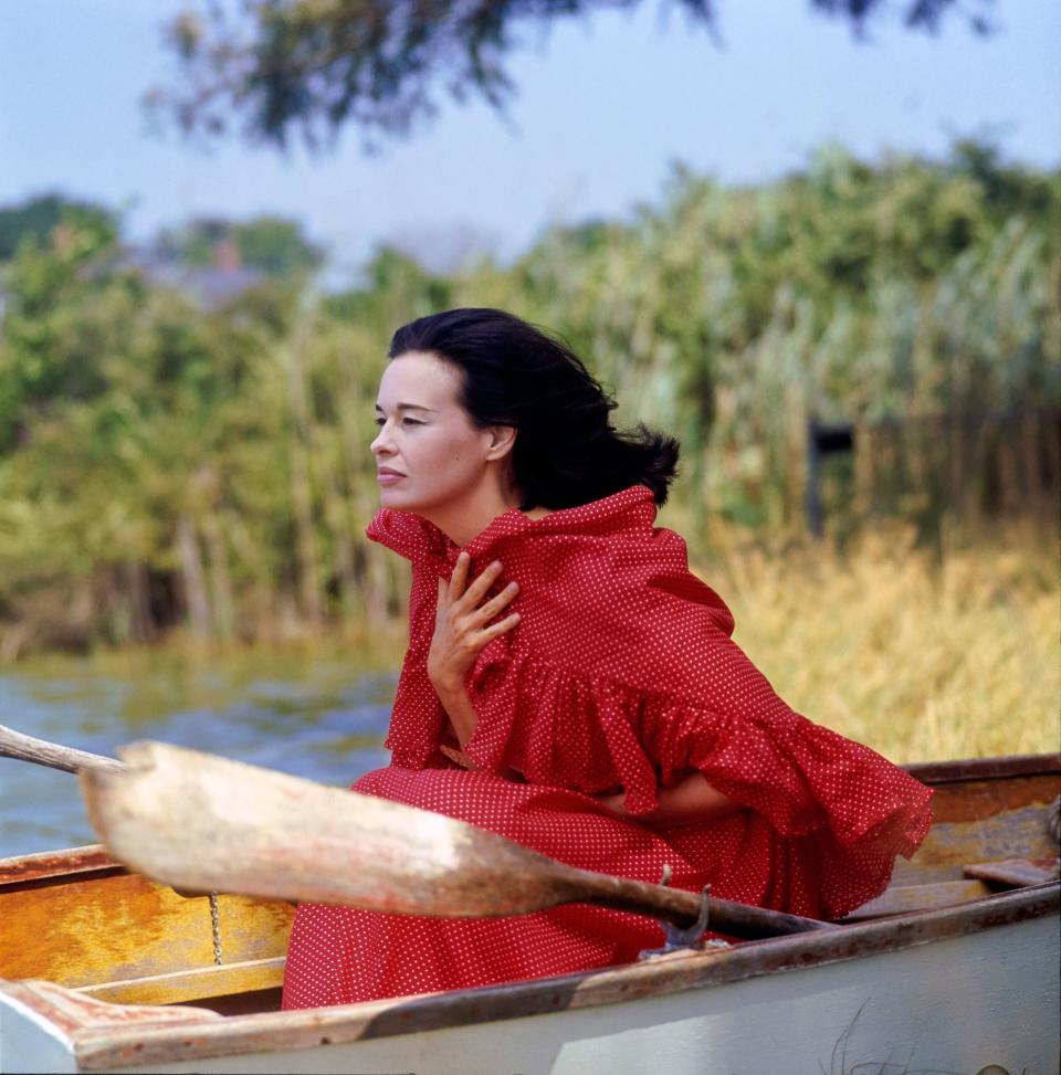 “Unruffled in ruffles, an enchanting bikini dress of red-and-white cotton-dotted Swiss, worn by Mrs. Cooper who, as Gloria Vanderbilt, will follow her successful exhibition of paintings at New York’s Hammer Galleries with another one-woman show this spring. The dress—with a huge ruffly circle of shawl covering the tiniest strip of bandeau, and a long, full skirt floating down to a deep double dust ruffle—by Anne Fogarty, of William Lind cotton. The coiffure by Miss Duval of the Kenneth Salon.”