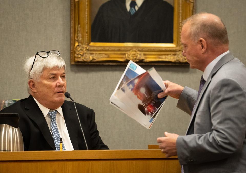 Defense attorney Doug O'Connell hands Mark Johnson, president of the Visual Law Group, screenshots of his digital recreation of the shooting during the trial Tuesday.