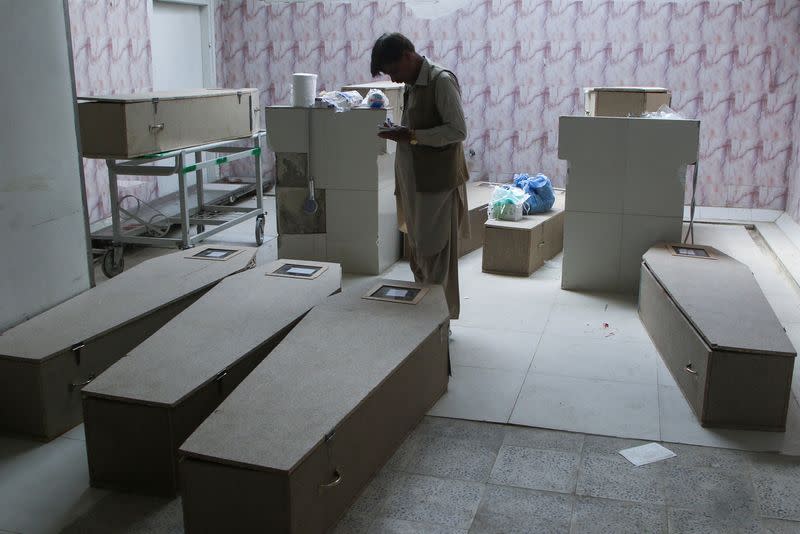 A man stands besides the coffin boxes, after gunmen shot and killed nine men after abducting them from a Iran-bound bus in Noshki district, at a hospital in Quetta