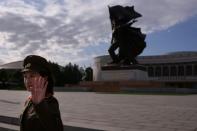 A uniformed tour guide gestures to tourists outside the War Museum in Pyongyang on October 9, 2015