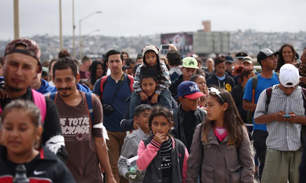Members of a caravan of migrants from Central America walk toward the US border.