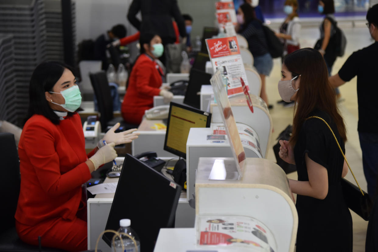 BANGKOK, THAILAND - MAY 01, 2020: A staff of Air Asia airline speaks with a passenger while wearing a face mask and gloves as a preventive measure at Don Muang International Airport during the Coronavirus (COVID-19) crisis. Low cost airline resuming its domestic operations from 1 May 2020 in service for passengers in need of travel. After flying was temporarily closed due to Covid-19 pandemic.- PHOTOGRAPH BY Yuttachai Kongprasert / Echoes Wire / Barcroft Studios / Future Publishing (Photo credit should read Yuttachai Kongprasert / Echoes Wire/Barcroft Media via Getty Images)