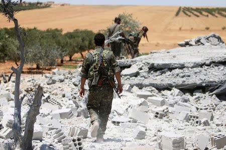 Fighters of the Syria Democratic Forces (SDF) walk on the rubble of a post that the SDF said belonged to Islamic State militants, in the western rural area of Manbij, in Aleppo Governorate, Syria June 11, 2016. REUTERS/Rodi Said