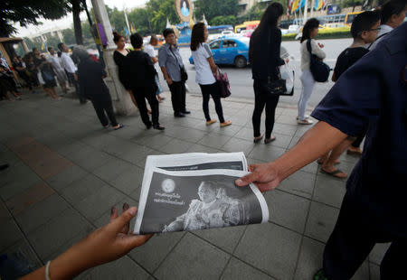 Commuters are handed out newspapers carrying the headlines of the passing of Thailand's King Bhumibol Adulyadej in Bangkok, Thailand October 14, 2016. REUTERS/Edgar Su