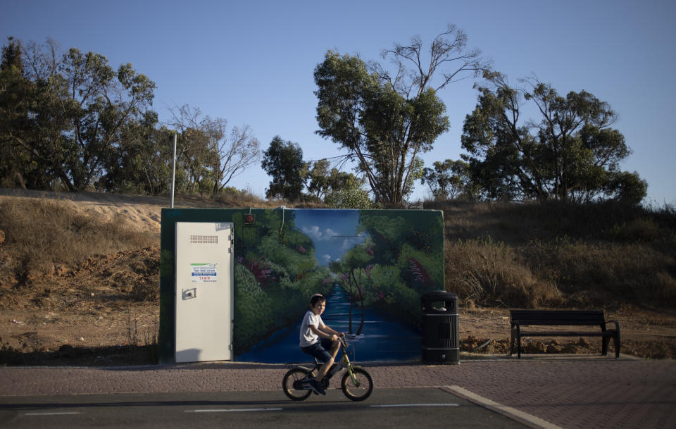 A boy rides his bicycles past a painted concrete bomb shelter placed in a public park in Sderot, Israel, July 21, 2021. No place in Israel has been hit harder by Palestinian rocket fire than Sderot, a working-class town just about a mile (1.5 kilometers) from the Gaza border. Although Sderot is enjoying an economic boom and revival, a generation of children and parents are suffering from the traumatic effects of two decades of rocket fire that experts are still struggling to understand. (AP Photo/Ariel Schalit)