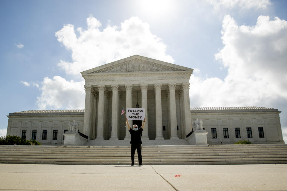 Bill Christeson holds up a sign that reads "Follow the Money" outside the Supreme Court, Thursday, July 9, 2020, in Washington. (AP Photo/Andrew Harnik)