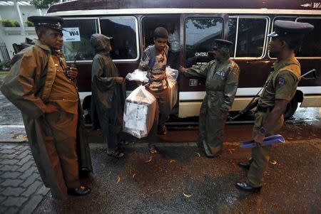 Police officers escort a polling officer carrying a sealed ballot box to a counting centre in Colombo, August 17, 2015. REUTERS/Dinuka Liyanawatte