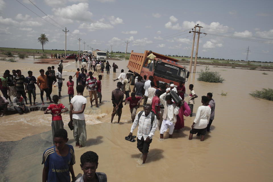 FILE - People walk on a flooded road after a heavy rainfall in the village of Aboud in the El-Manaqil district of the Al-Jazirah Province of Sudan, August 22 2022. A Sudanese official said Wednesday Aug. 31, 2022, that flash floods triggered by heavy monsoon rains across much of Sudan have killed at least 100 people and injured at least 96 others since the start of the rainy season in May. The United Nations says at least 258,000 people have been affected by floods in 15 of Sudan’s 18 provinces. (AP Photo/Marwan Ali, File)