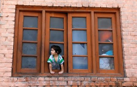 A girl looks out from a window of her house during a curfew in Srinagar, July 24, 2016. REUTERS/Danish Ismail