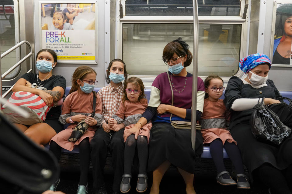 A family, some wearing face masks and some not, ride the subway, Monday, Sept. 14, 2020, in the Brooklyn borough of New York. The Metropolitan Transportation Authority announced a new public service campaign to encourage mask usage as well as a new $50 fine policy for those who refuse to wear face coverings on subways, buses and commuter railroads. (AP Photo/Mary Altaffer)