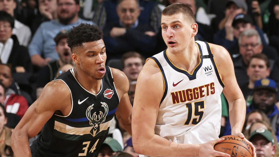 Nikola Jokic looks to pass the ball as Giannis Antetokounmpo defends him.