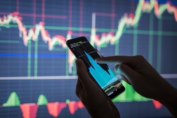 Person pointing to stock chart on a smartphone.