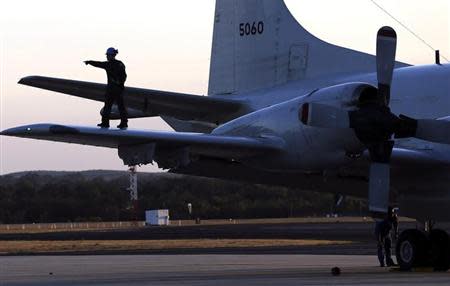 An aircrew walks on the wing of a Japanese Air Force AP-3C Orion after it landed at RAAF Pearce Base before it joins the search for missing Malaysian Airlines flight MH370 in Perth March 23, 2014. REUTERS/Rob Griffith/Pool