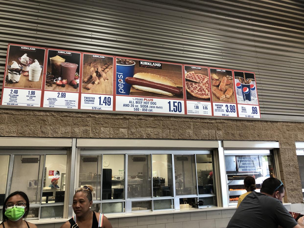 A Costco Business Center food court with the food court menu pictured above it.