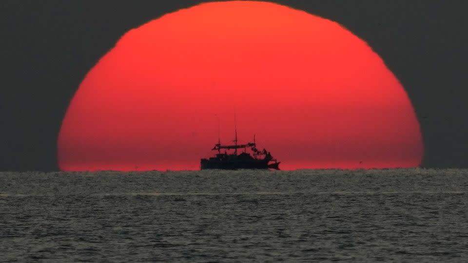 A fishing boat passes by a setting sun in the Sulu Sea. - Aaron Favila/AP