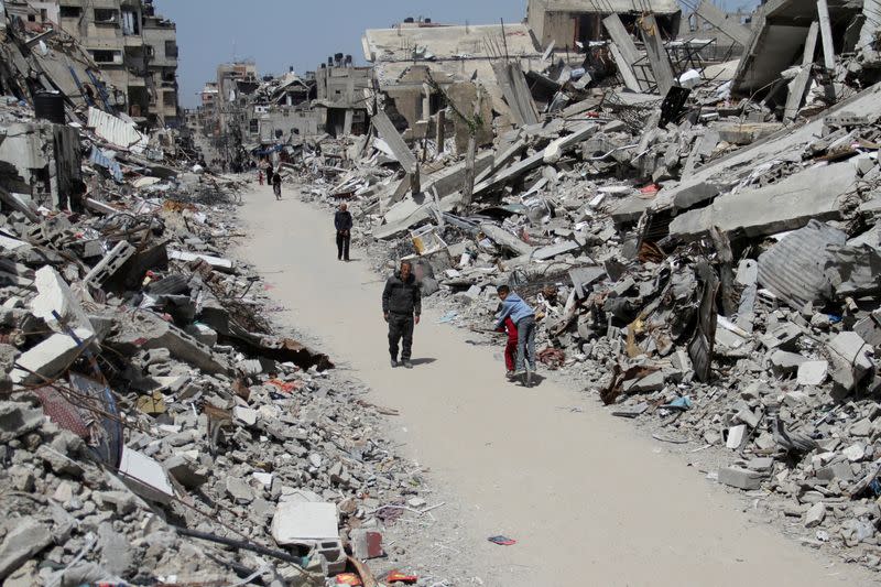 FILE PHOTO: Palestinians walk past the ruins of houses and buildings destroyed during Israel’ military offensive, in the northern Gaza Strip