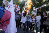 Chinese protesters burn a Japanese flag near posters claiming Diaoyu islands, as known in China and Senkaku in Japan, belong to China and to fire upon Japan during a protest near the Japanese Embassy in Beijing, China, Tuesday, Sept. 18, 2012. The 81st anniversary of a Japanese invasion brought a fresh wave of anti-Japan demonstrations in China on Tuesday, with thousands of protesters venting anger over the colonial past and a current dispute involving contested islands in the East China Sea. (AP Photo/Ng Han Guan)