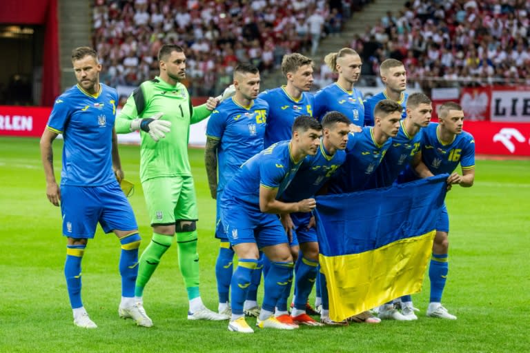 El equipo titular de Ucrania posa con la bandera de su país para la foto oficial previa al partido amistoso contra Polonia, en Varsovia el 7 de junio de 2024 (Wojtek Radwanski)