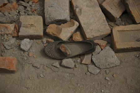 A woman's shoe lies among the debris of a collapsed house a day after an earthquake in Bhaktapur, Nepal April 26, 2015. REUTERS/Navesh Chitrakar