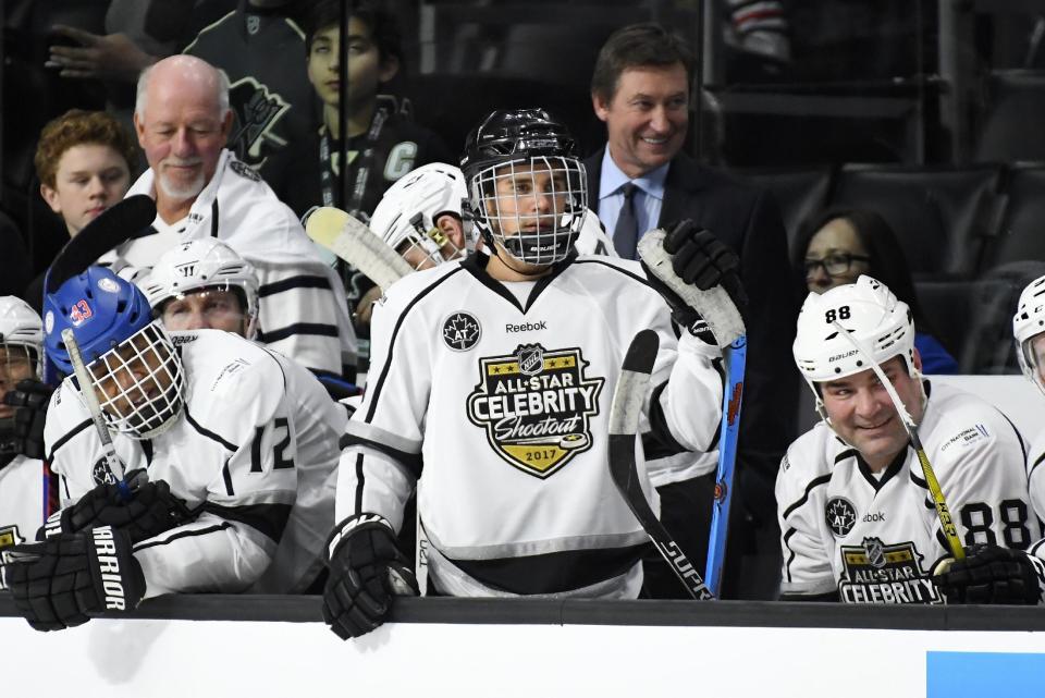 Celebrity players, from left, Cuba Gooding Jr., Justin Bieber and Eric Lindros sit on the bench as Team Gretzky head coach Wayne Gretzky, top center, stands in the background during the first period of the NHL All-Star Celebrity Shootout at Staples Center, Saturday, Jan. 28, 2017, in Los Angeles. The NHL All-Star Game is scheduled to be played at Staples Center on Sunday. (AP Photo/Mark J. Terrill)