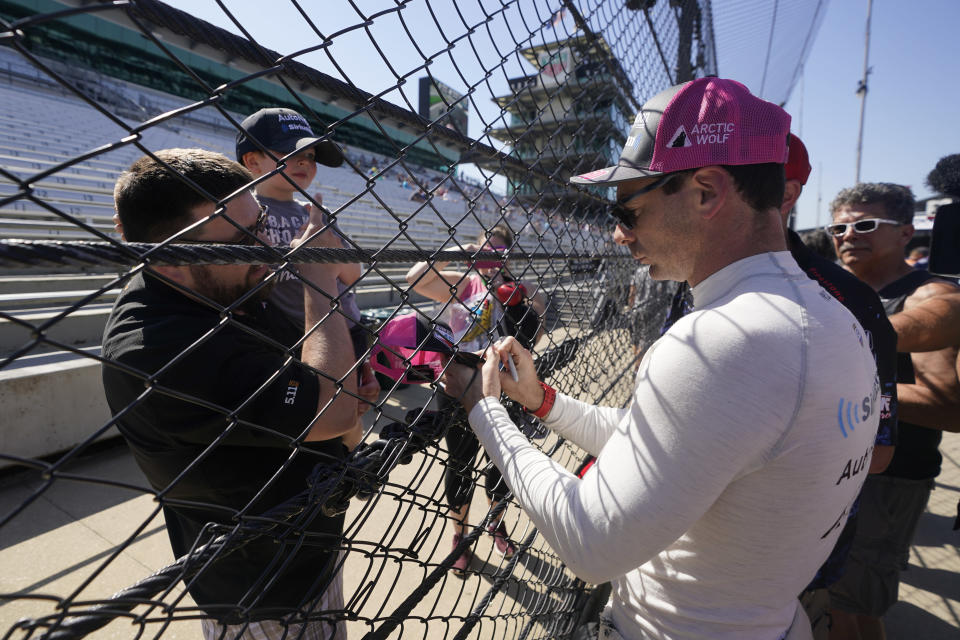 Simon Pagenaud, of France, signs autographs for fans during practice for the Indianapolis 500 auto race at Indianapolis Motor Speedway, Tuesday, May 17, 2022, in Indianapolis. (AP Photo/Darron Cummings)