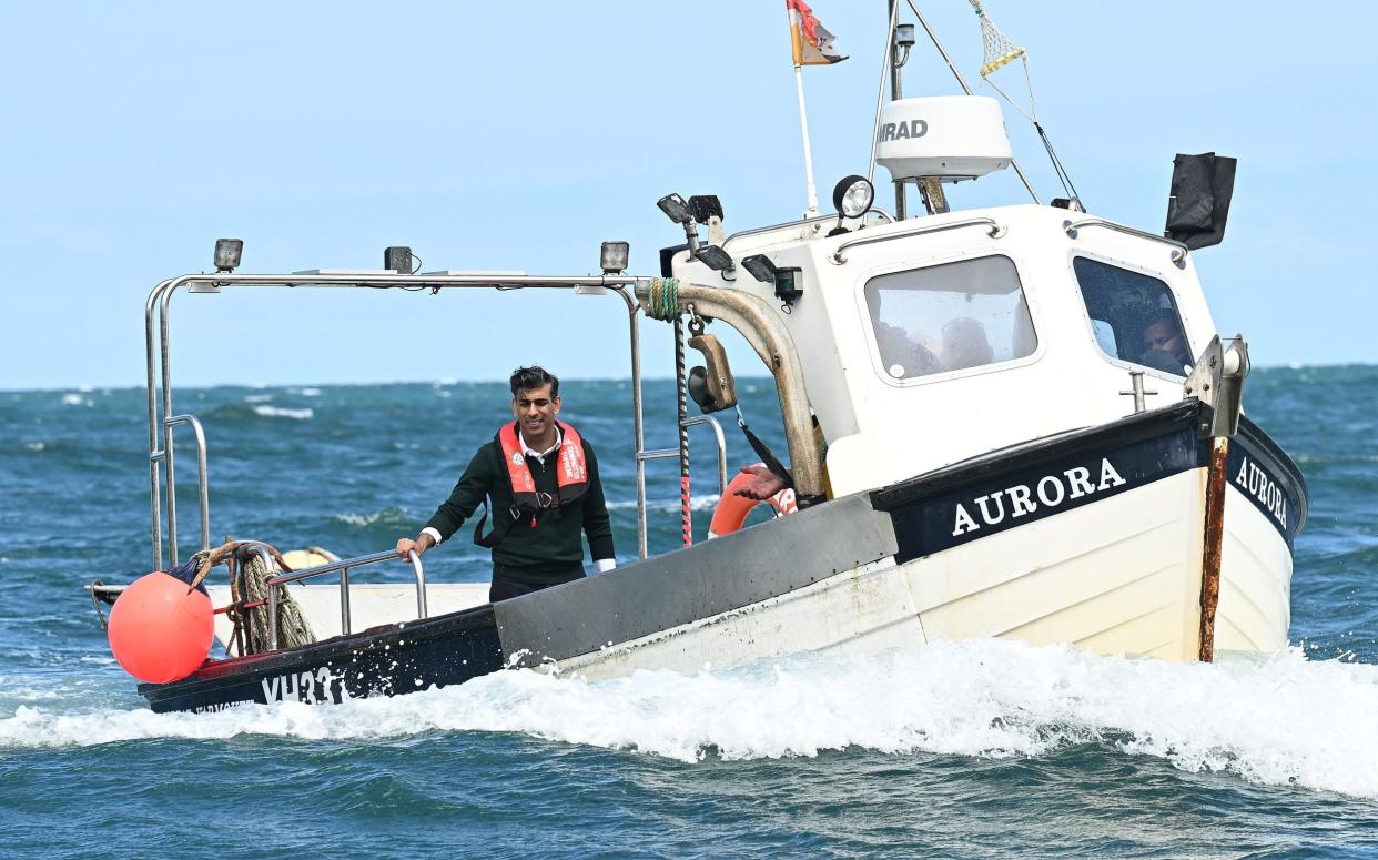 Prime Minister Rishi Sunak rides on a boat in the harbour at Clovelly, Devon as he inspected lobster pots