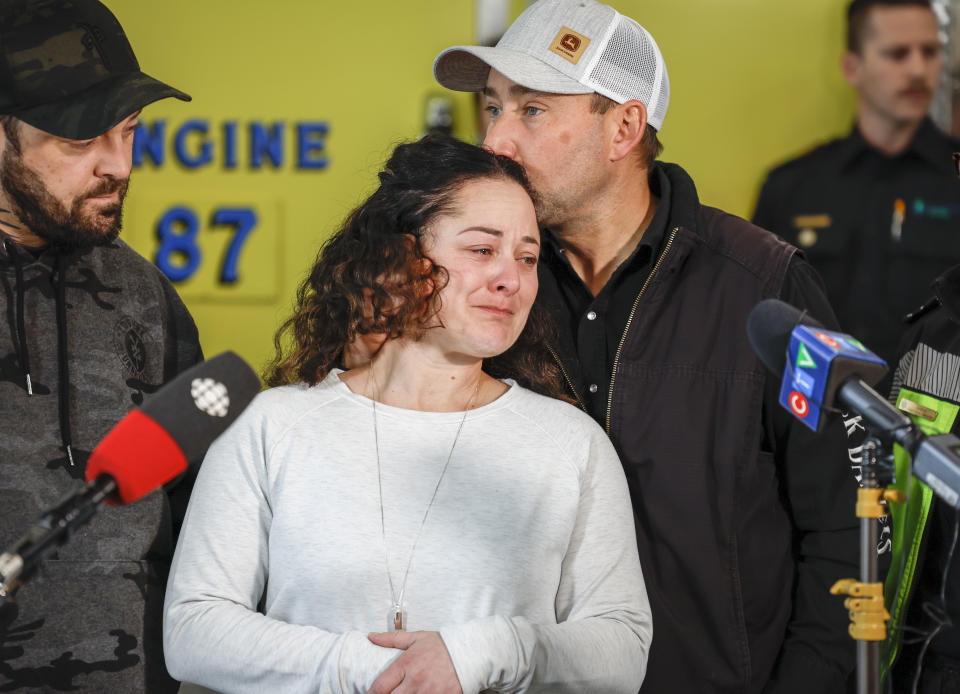 Paramedic Jayme Erickson, center, who was called to a crash last week and didn't know she was trying to save her own daughter because the injuries were too severe, is comforted by her husband Sean Erickson, as she speaks to the media in Airdrie, Alberta, Tuesday, Nov. 22, 2022. (Jeff McIntosh/The Canadian Press via AP)