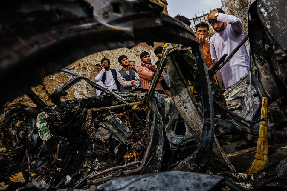 Relatives and neighbors of the Ahmadi family gathered on Aug. 30, 2021, around the incinerated husk of a vehicle targeted a day earlier by the American drone strike.