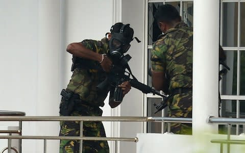  Sri Lankan Special Task Force (STF) personnel in gas masks are pictured outside a house during a raid  - Credit: AFP/ISHARA S. KODIKARA