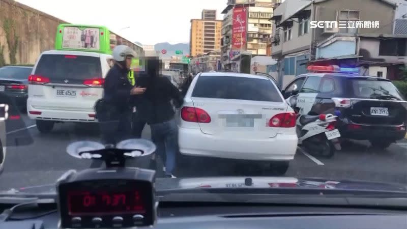 員警包圍轎車，將駕駛帶下車。