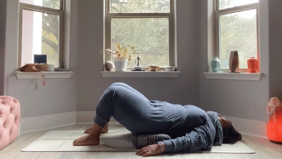 Woman lying on her back in her bedroom to stretch her low back