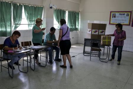 A woman casts her marked ballot in a box during opposition coalition primaries for parliamentary election Caracas May 17, 2015. REUTERS/Marco Bello