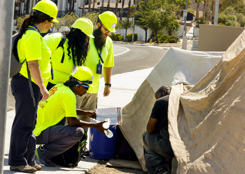 Help of Southern Nevada outreach workers talk to Darryl Walker, right, a homeless person in Las Vegas, on Tuesday, July 9, 2024, in Las Vegas. Help of Southern Nevada travels the streets with flyers about heat, water and vehicles to transport people to cooling centers. (Bizuayehu Tesfaye/Las Vegas Review-Journal via AP)