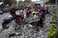 Rescuers clear debris from buried vehicles after an earthquake struck Cebu city, in central Philippines October 15, 2013. A strong earthquake measuring 7.2 struck islands popular with tourists in the Philippines on Tuesday killing at least 20 people, some while praying in a centuries-old church, officials said. (REUTERS/Erik De Castro)