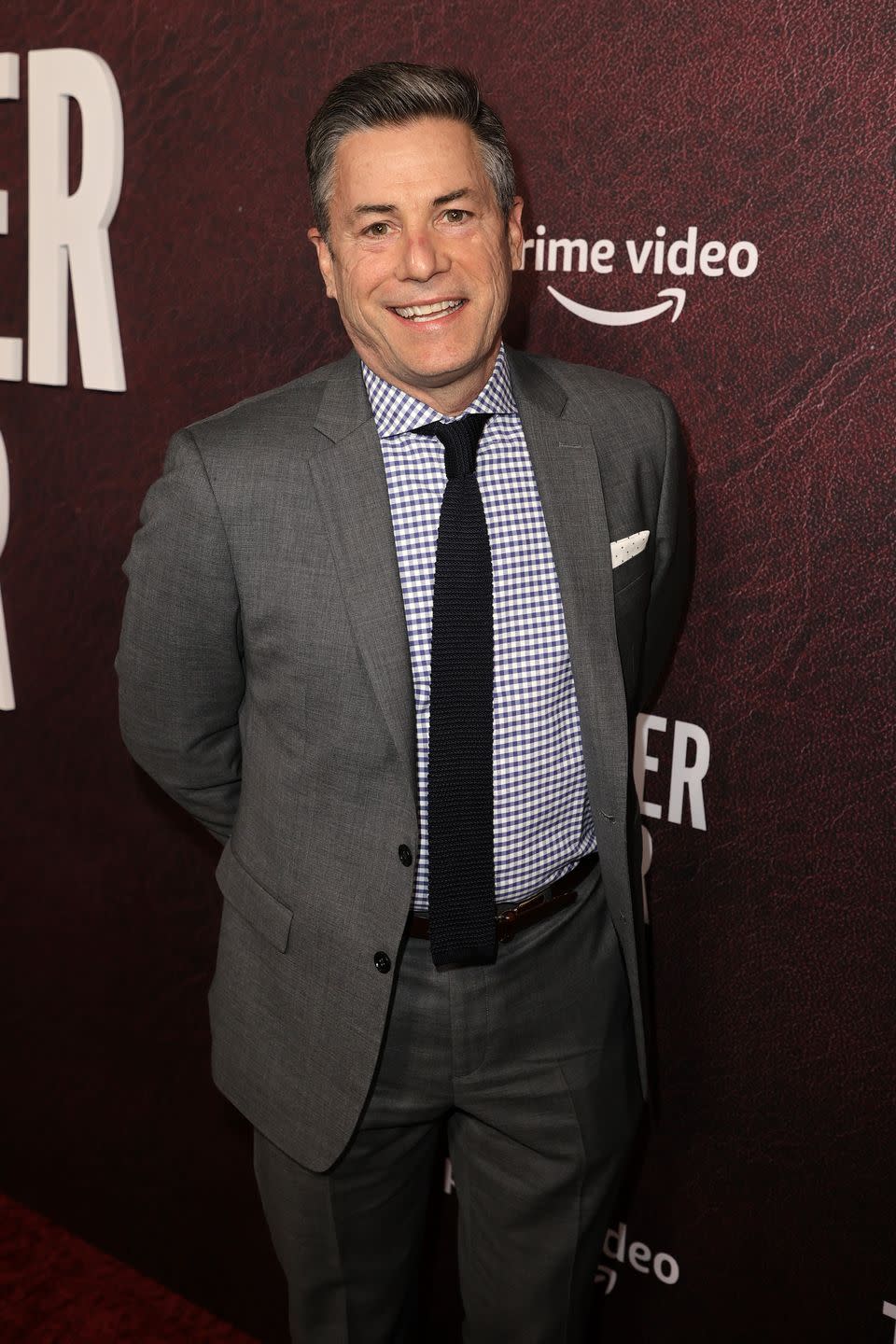 the author j r moehringer smiling on a red carpet he has grey hair and is wearing a grey suit and checkered shirt