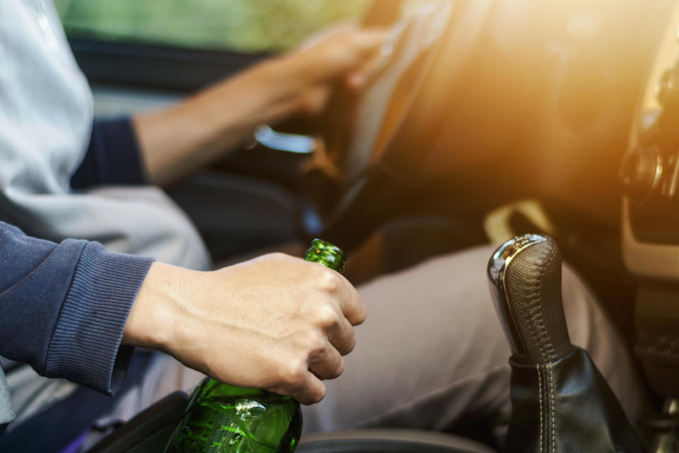 A person is holding a green bottle while driving a car