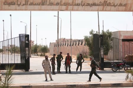 Kurdish fighters stand on the entrance of "The Sports city of the martyr Bassel Hafez al-Assad" in the Ghwairan neighborhood of Hasaka, Syria, August 23, 2016. Bassel Hafez al-Assad is the brother of Syria's President Bashar al-Assad. REUTERS/Rodi Said