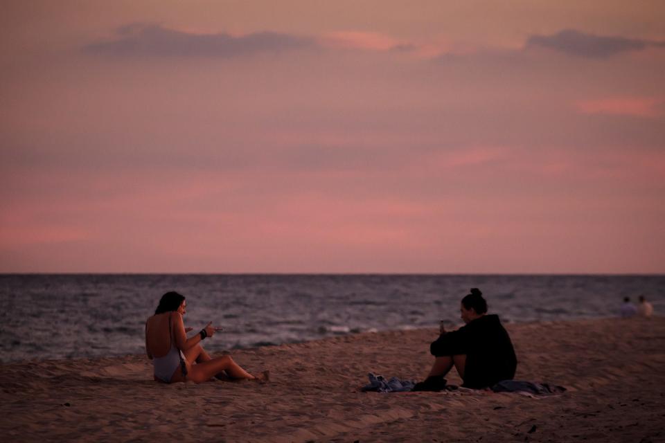 The sun sets on beachgoers in Delray Beach, Fla., on Thursday, January 21, 2021.