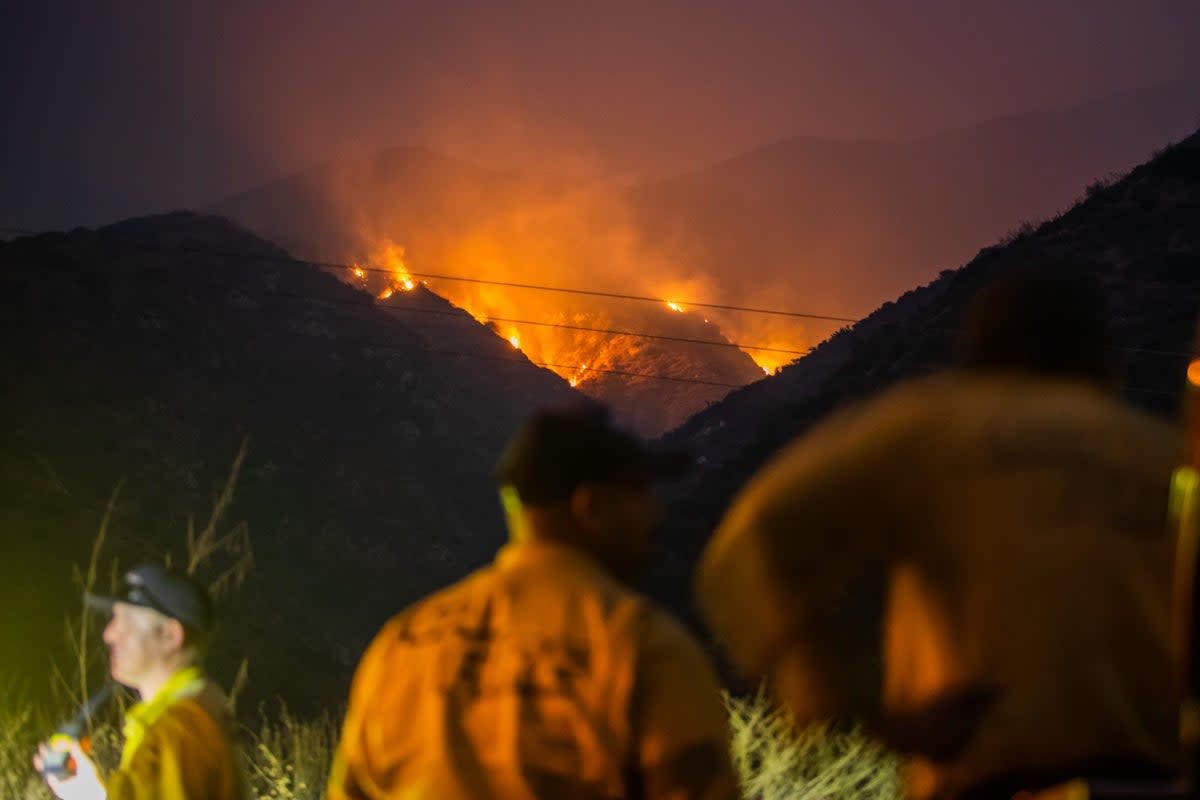 Firefighters watch as the Line Fire burns in the foothills of the San Bernardino Mountains on Sunday. The fire has forced evacuation orders for thousands of Southern California residents. Several school districts canceled school on Monday. ((Photo by Apu Gomes/Getty Images))