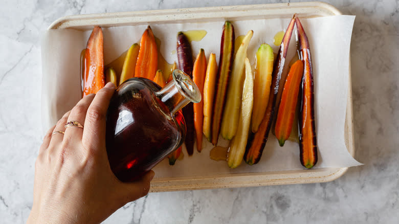 pouring maple on carrots on baking sheet