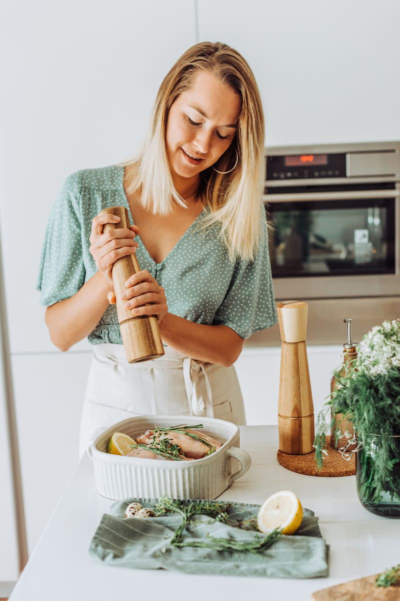 A woman grinding pepper over food