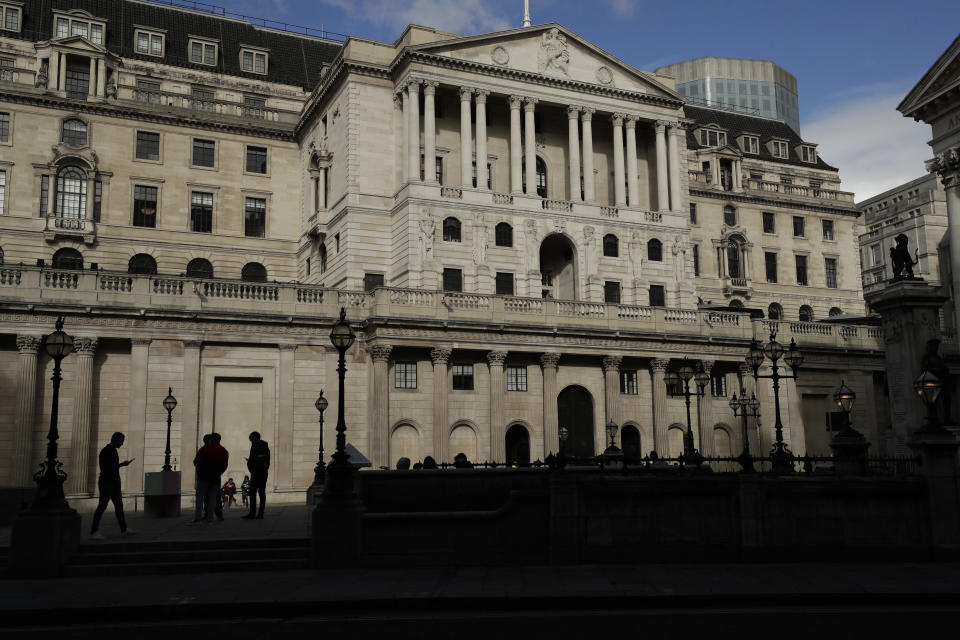 People stand outside the Bank of England, in the City of London, Thursday, Oct. 15, 2020. London will be moved into a coronavirus Tier 2 lockdown as part of the British governments new alert system for rising case numbers, starting midnight local time on Friday night into Saturday. The new restrictions will include stopping different households from mixing indoors and people should aim to avoid public transport if they can. (AP Photo/Matt Dunham)