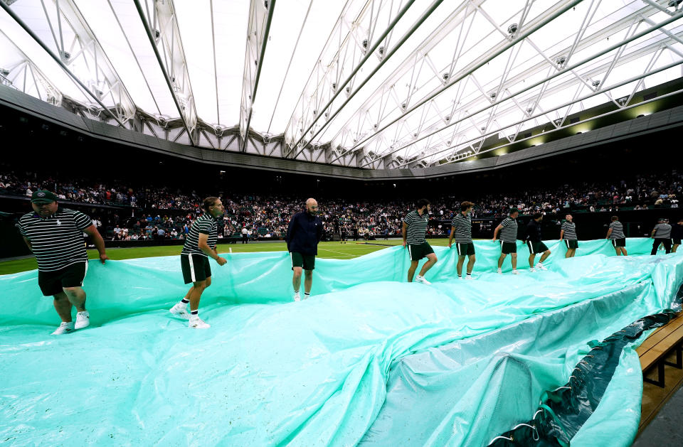 Rain covers are removed from centre court at Wimbledon.