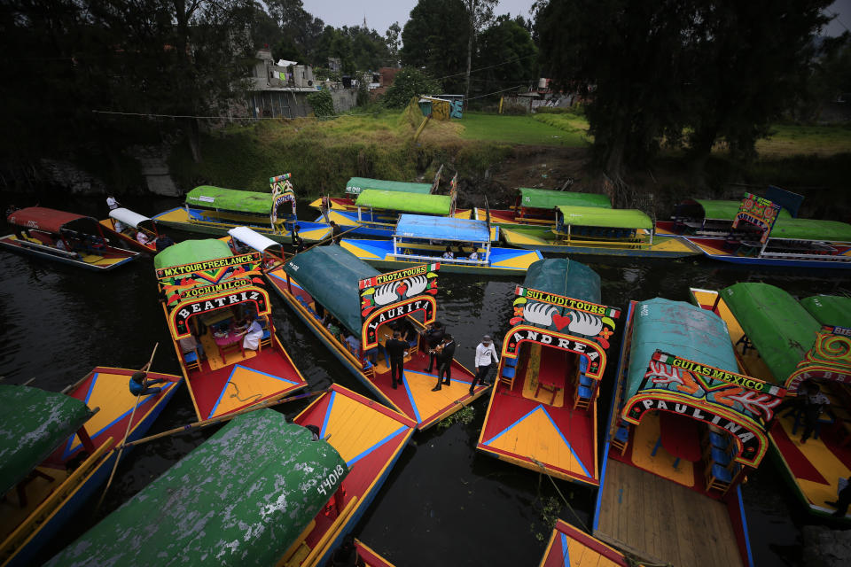 In this Sept. 6, 2019, photo, boats carrying passengers come in to dock amidst parked "trajineras," the colorful passenger boats typically rented by tourists and families in Xochimilco, Mexico City. The usually festive Nativitas pier was subdued and largely empty Friday afternoon, with some boat operators and vendors estimating that business was down by 80% on the first weekend following the drowning death of a youth that was captured on cellphone video and seen widely in Mexico. Borough officials stood on the pier to inform visitors of new regulations that went into effect Friday limiting the consumption of alcohol, prohibiting the use of speakers and instructing visitors to remain seated. (AP Photo/Rebecca Blackwell)
